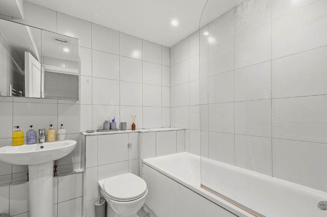 Bright bathroom with white tiling, bath and basin