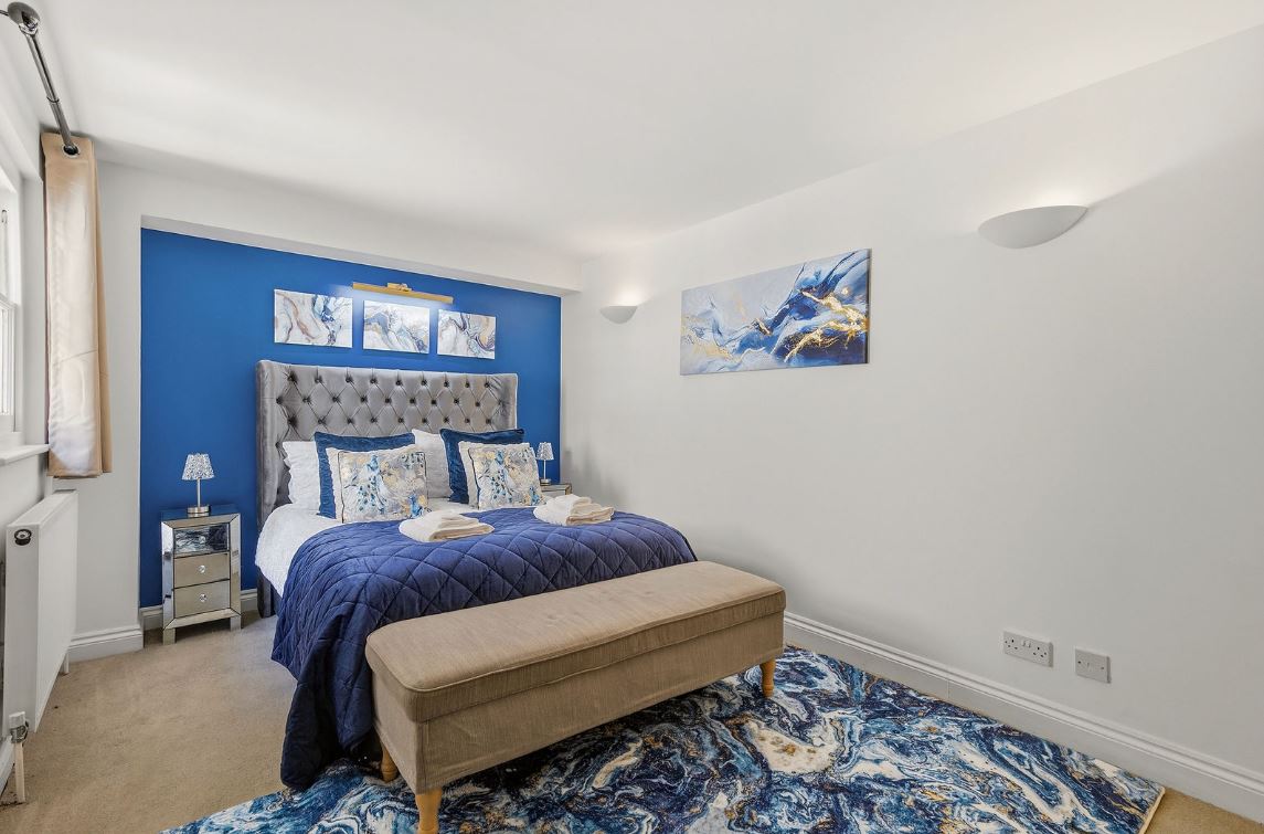 Luxury bedroom with dressed bed and blue feature wall